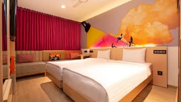 Habitación de hotel con cama, sofá, televisión y un mural en la pared.