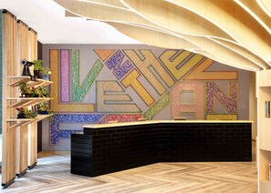 Un área de recepción con diseño moderno, que presenta una pared grande con patrones geométricos y la palabra “LETHAN” mostrada de forma destacada.