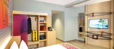 Una habitación de hotel moderna con una cama, un armario, un televisor y un espacio de escritorio.