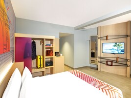 A modern hotel room with a bed, a wardrobe, a television, and a desk area.