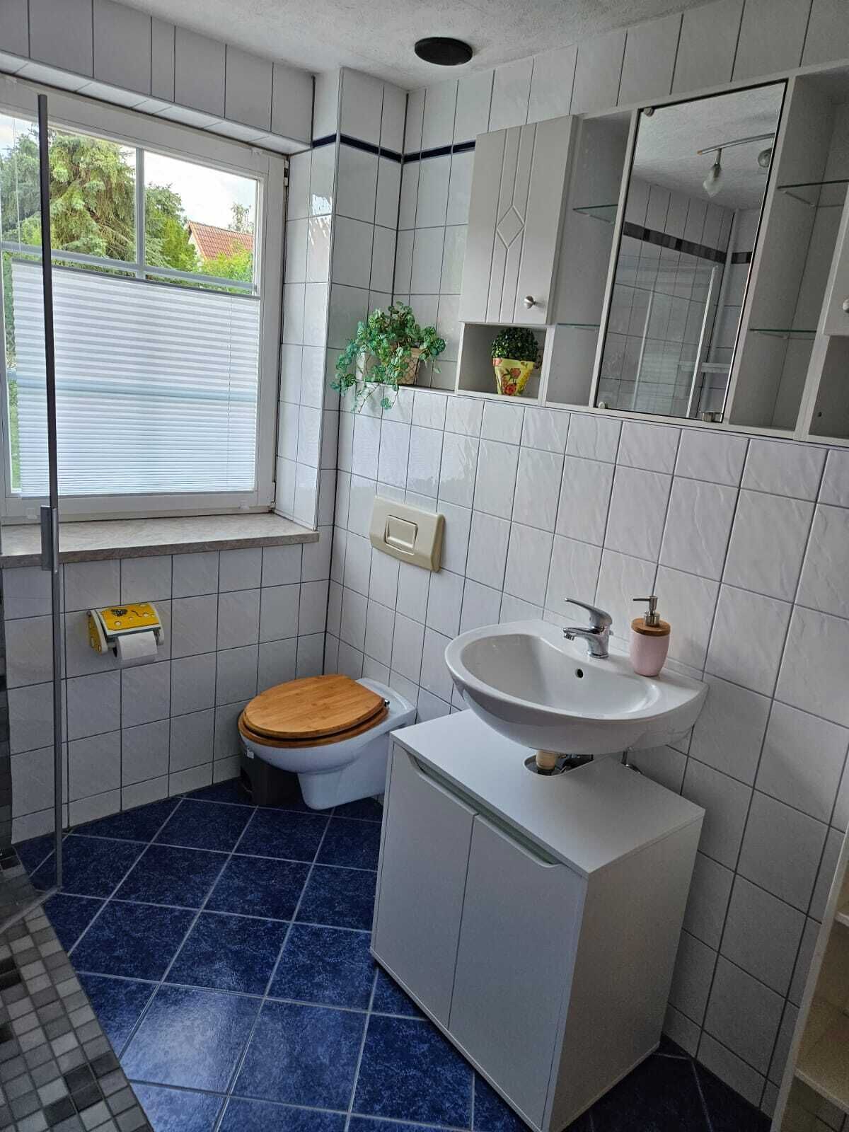 A small bathroom with a toilet, sink, and window.