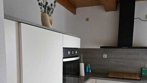 Eine moderne Küche mit weißen Schränken, einem eingebauten Backofen und einer Küchenwand mit Steinfliesen.