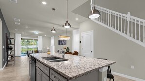 A modern kitchen with granite countertops, stainless steel appliances, and pendant lighting. - Poolside Oasis · Family Home Close to Disney (Davenport)