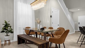 A dining area with a glass-top table, wooden bench, and orange chairs. - Poolside Oasis · Family Home Close to Disney (Davenport)