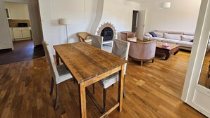A living room with a wooden dining table, two chairs, a sofa, and a television. - House in Drôme Provençale (Dieulefit)