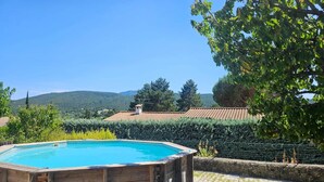 A wooden hot tub in a garden with a view of hills and a tiled roof building in the background. - House in Drôme Provençale (Dieulefit)