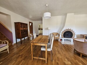 Cozy living area with a large wooden table, comfortable armchair, and a modern fireplace.