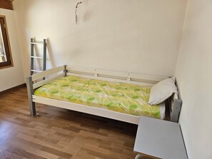 Cozy retreat with a single bed, white desk, and comfortable chair.