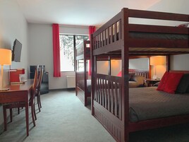 Habitación con literas, escritorio, silla y televisor.