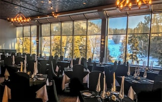 Un restaurante con mesas dispuestas para comer, amplias ventanas con vista a un paisaje nevado.