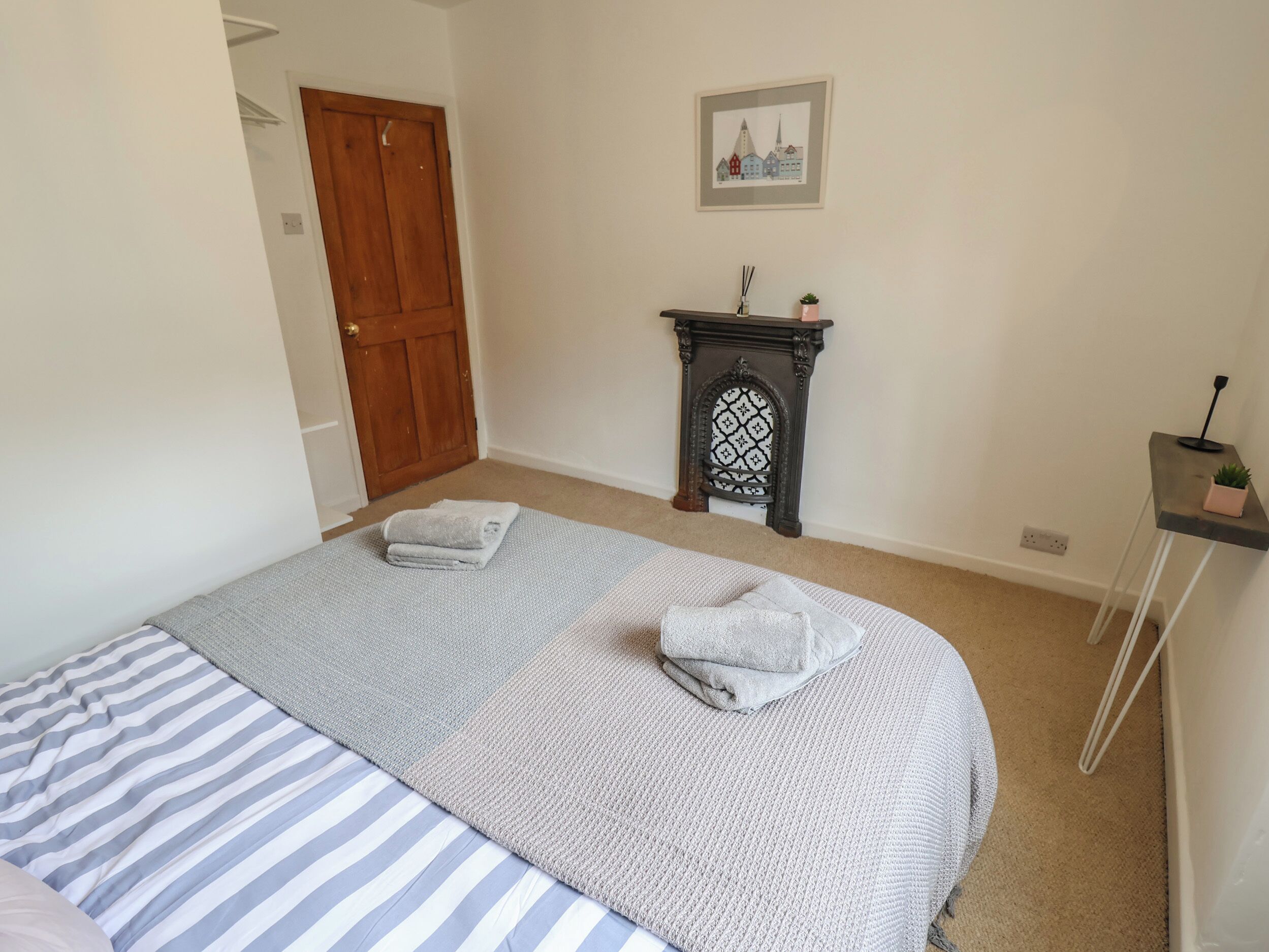 Une chambre à coucher avec un lit, une porte en bois, une cheminée et une petite table sur laquelle est posée une plante.