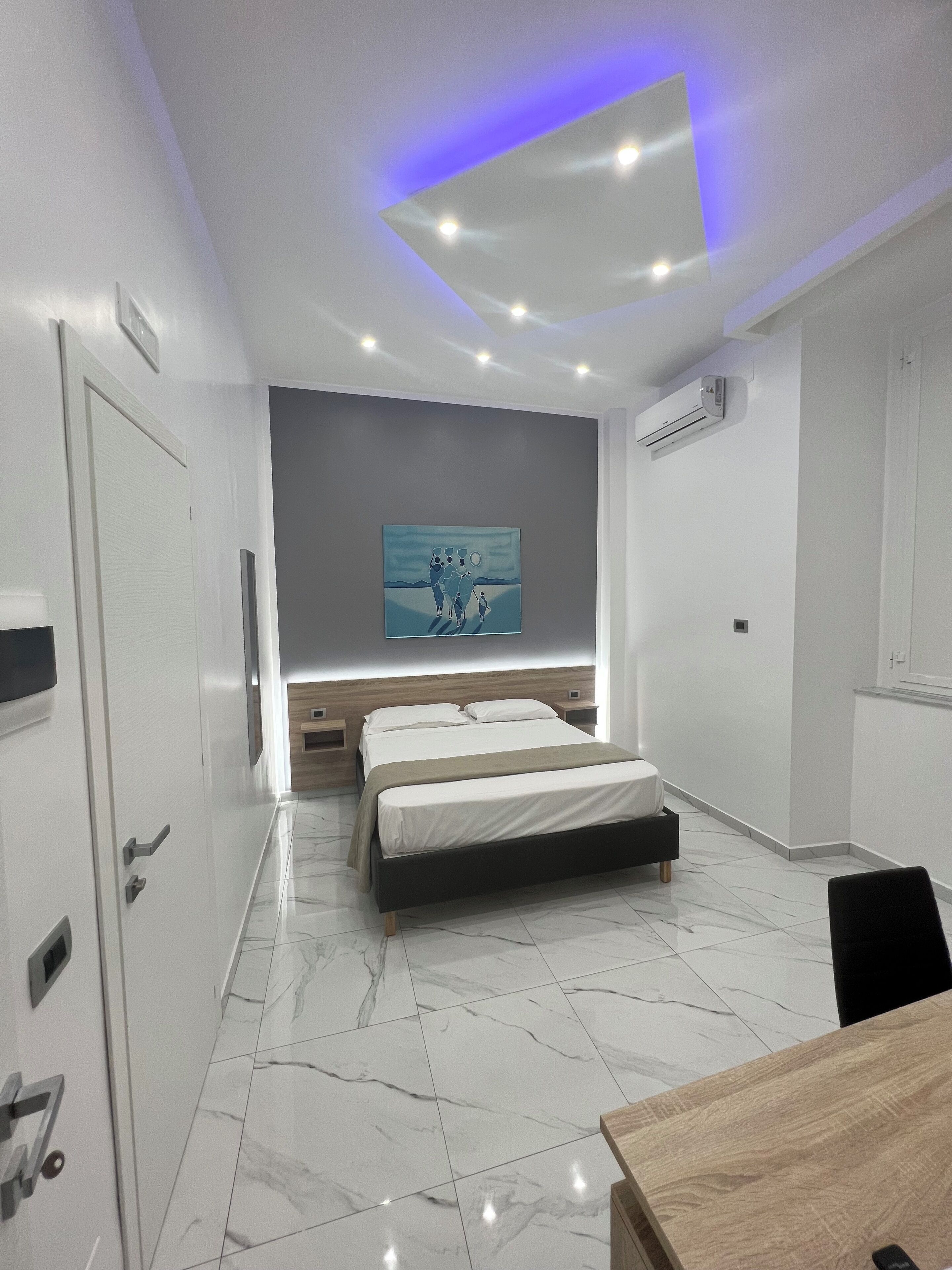 Une chambre à coucher moderne avec un lit, des tables de chevet, un tableau au mur et un appareil de climatisation.