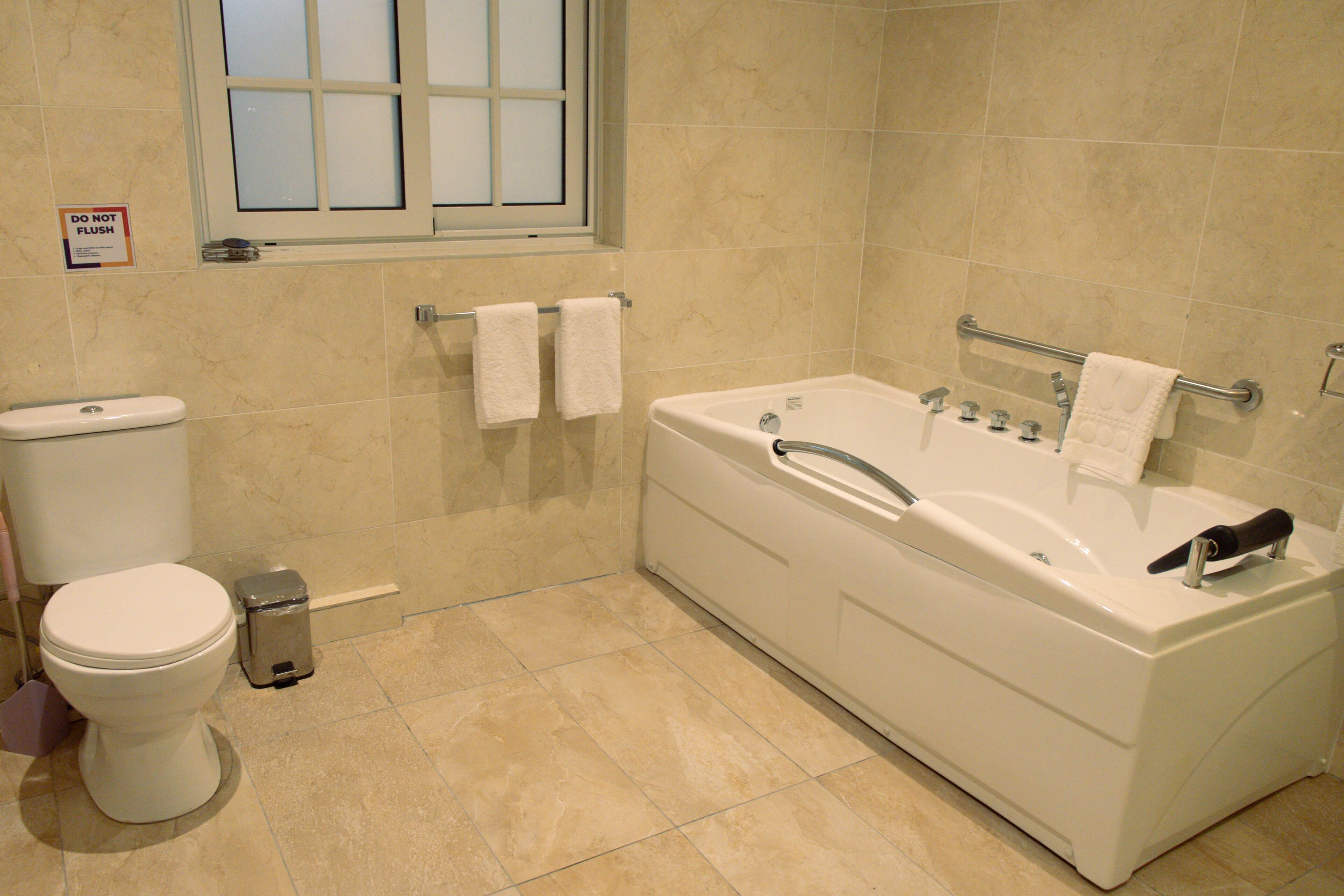A bathroom with a toilet, a bidet, a bathtub, and a window.