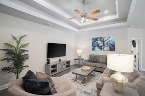 Relax in this stylish living room with a ceiling fan, flat-screen TV, and comfortable sofa.