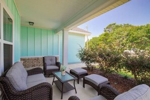 Relax in a serene outdoor seating area with wicker furniture and cushioned chairs, surrounded by a brick wall and wooden deck.