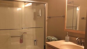 Une salle de bain avec une douche à parois de verre, des toilettes, un lavabo et des meubles en bois.
