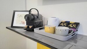 Un coin café équipé d’une machine à café, de tasses et de dosettes de café, le tout disposé sur un plateau.