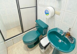 A bathroom with a toilet, sink, and a trash bin. - Sol y Mar, Galápagos (San Cristóbal)