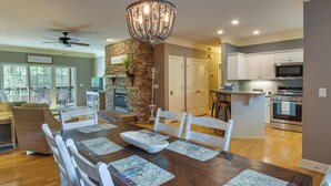A dining area with a wooden table, white chairs, and a chandelier. - Clayton Resort Getaway w/ Pool Access, Pickleball! (Clayton)