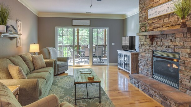 A living room with a fireplace, a sofa set, a coffee table, and a view through glass doors to an outdoor patio area. - Clayton Resort Getaway w/ Pool Access, Pickleball! (Clayton)