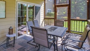 An outdoor patio with a table and chairs, a lantern, and a sliding glass door leading to a deck. - Clayton Resort Getaway w/ Pool Access, Pickleball! (Clayton)