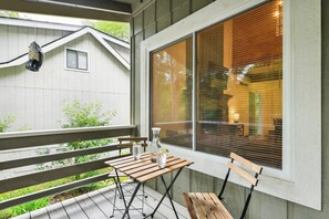 A wooden deck with a table and chairs, a hanging light fixture, and a window with blinds. - Maggie Valley Mtn Escape w/ Fire Pit & Deck (Maggie Valley)