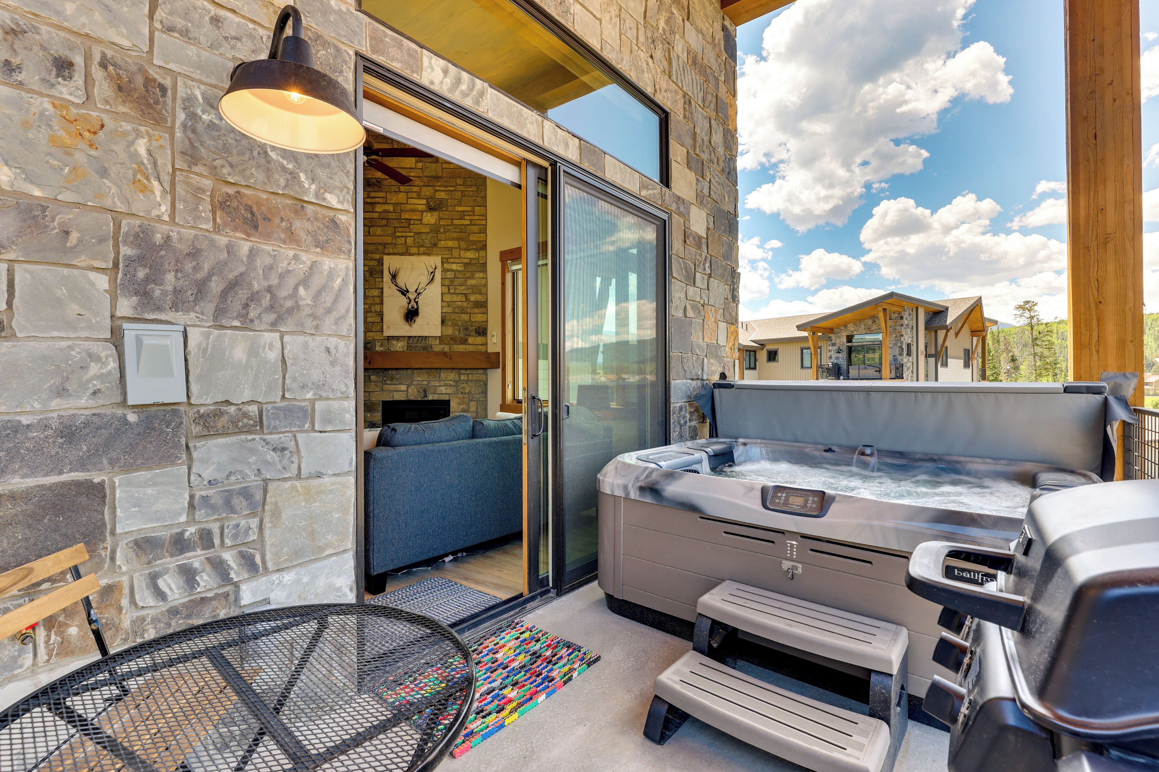 Une façade en pierre avec une porte en verre donnant sur une pièce où se trouvent un canapé bleu et un jacuzzi.