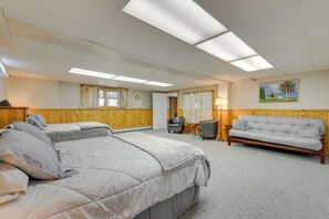 Una habitación de hotel con dos camas, un sofá, un escritorio y un cuadro en la pared.