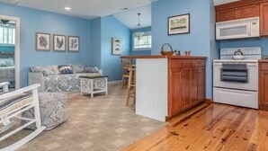 A compact living space with a kitchenette, a dining area, and a seating area with a patterned sofa. - Country living in a private setting, The Loft at Springhouse Farm (Rockbridge County)