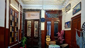 Una stanza accogliente con tappeto verde, porte in legno, una chitarra e un cartello di benvenuto.