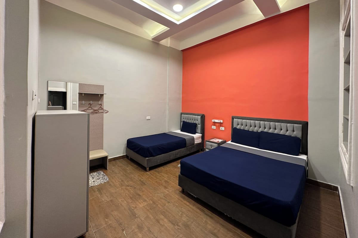 Ein Hotelzimmer mit zwei Betten, einem Kleiderschrank, einem Spiegel und einer roten Wand.