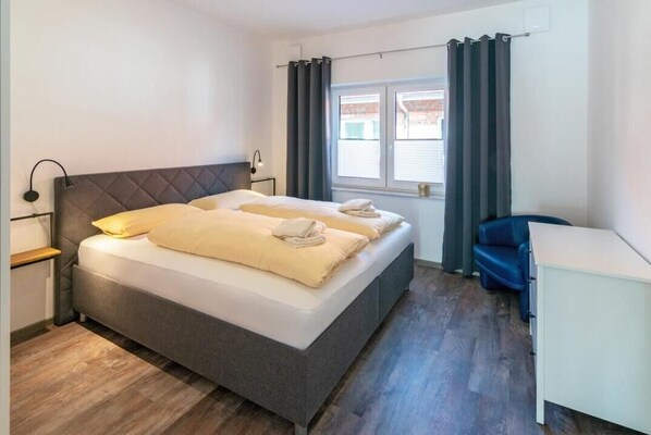 Ett modernt hotellrum med en stor säng, sängbord, ett skrivbord och ett fönster med gardiner.
