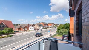 Een woonstraat met huizen, een heldere lucht en een verkeersbord met een snelheidslimiet van 30 km/u.