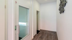 Un pasillo con puerta de vidrio, piso de madera y un adorno en la pared.