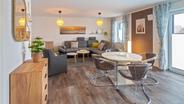 Una sala moderna con un sofá modular, una mesa de comedor redonda y un aparador de madera.