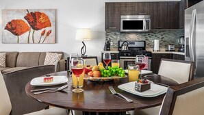 A modern kitchen with dark wood cabinets, stainless steel appliances, and a dining area with a round table set for a meal. - Condo 1 one bed, Palm Beach (Noord)