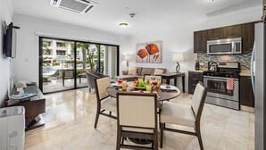 A modern kitchen with a microwave, oven, and a dining area with a table and chairs. - Condo 1 one bed, Palm Beach (Noord)