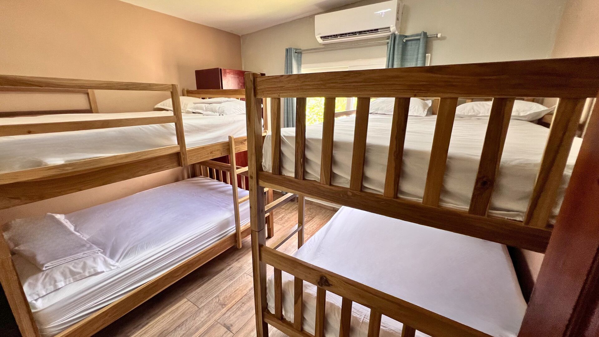 A room with bunk beds, a window, and an air conditioning unit.