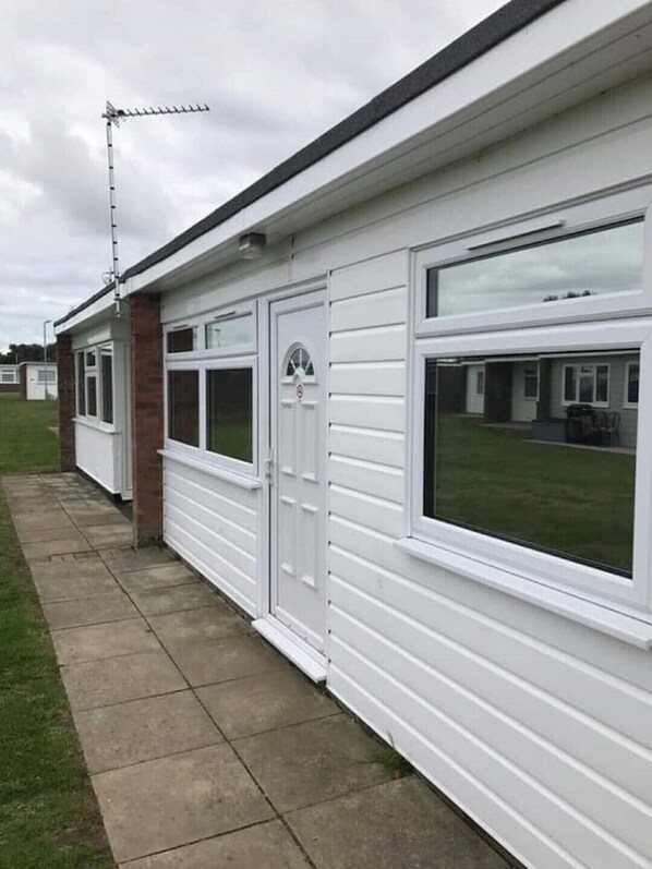 A row of white mobile homes with large windows and a visible antenna on the roof.