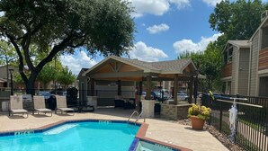 A rectangular pool with a 4 ft 6 in depth and 3 ft 6 in width, surrounded by a covered seating area with chairs and a table, and a potted plant. - Cozy 1BR Apt in Medical Center. Close to Downtown/ Zoo/ Medical Center  (Houston)