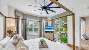 Un dormitorio amplio con una cama grande, televisión y vistas a la playa a través de amplios ventanales.