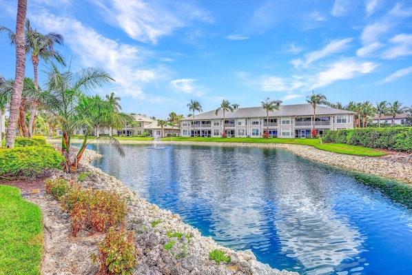 A resort with a water feature, palm trees, and a large building with multiple windows.