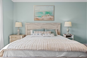 A bedroom with a bed, two bedside tables, and a wall-mounted painting.