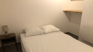 A small, neatly made bed with white bedding in a room with a simple, clean design. - Près du Parc de Verdure (Chomérac)