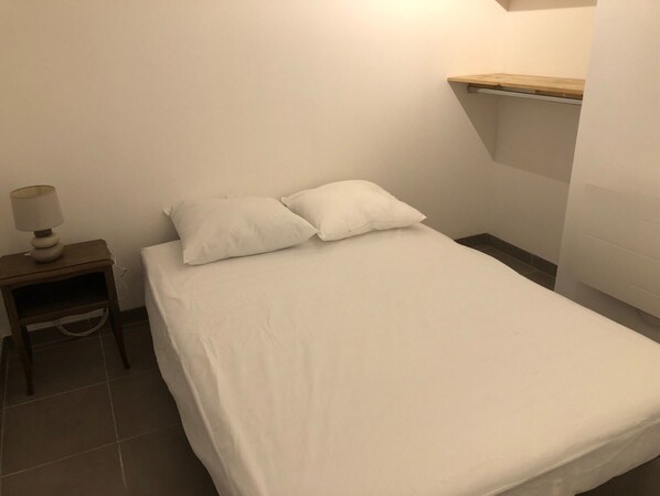 A small, neatly made bed with white bedding in a room with a simple, clean design. - Près du Parc de Verdure (Chomérac)
