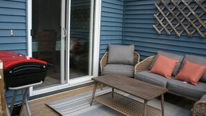 A patio with a grill, a sofa, and a table.
