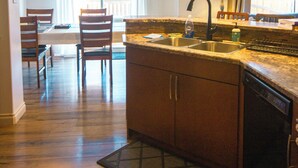 A kitchen with wooden cabinets, a sink, and a dining area with chairs and a table.