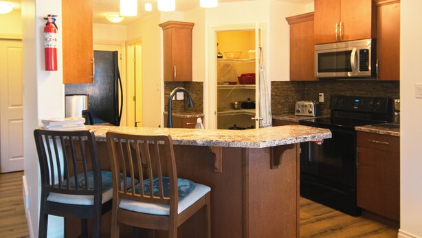 A modern kitchen with wooden cabinets, a stainless steel microwave, and a central island with bar stools.
