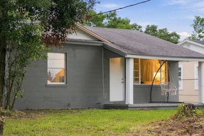 A residential house with a grey exterior, a front porch, and a visible window.
