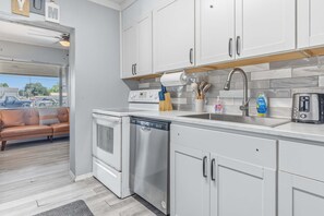 A modern kitchen with white cabinetry, a stainless steel dishwasher, and a built-in oven.